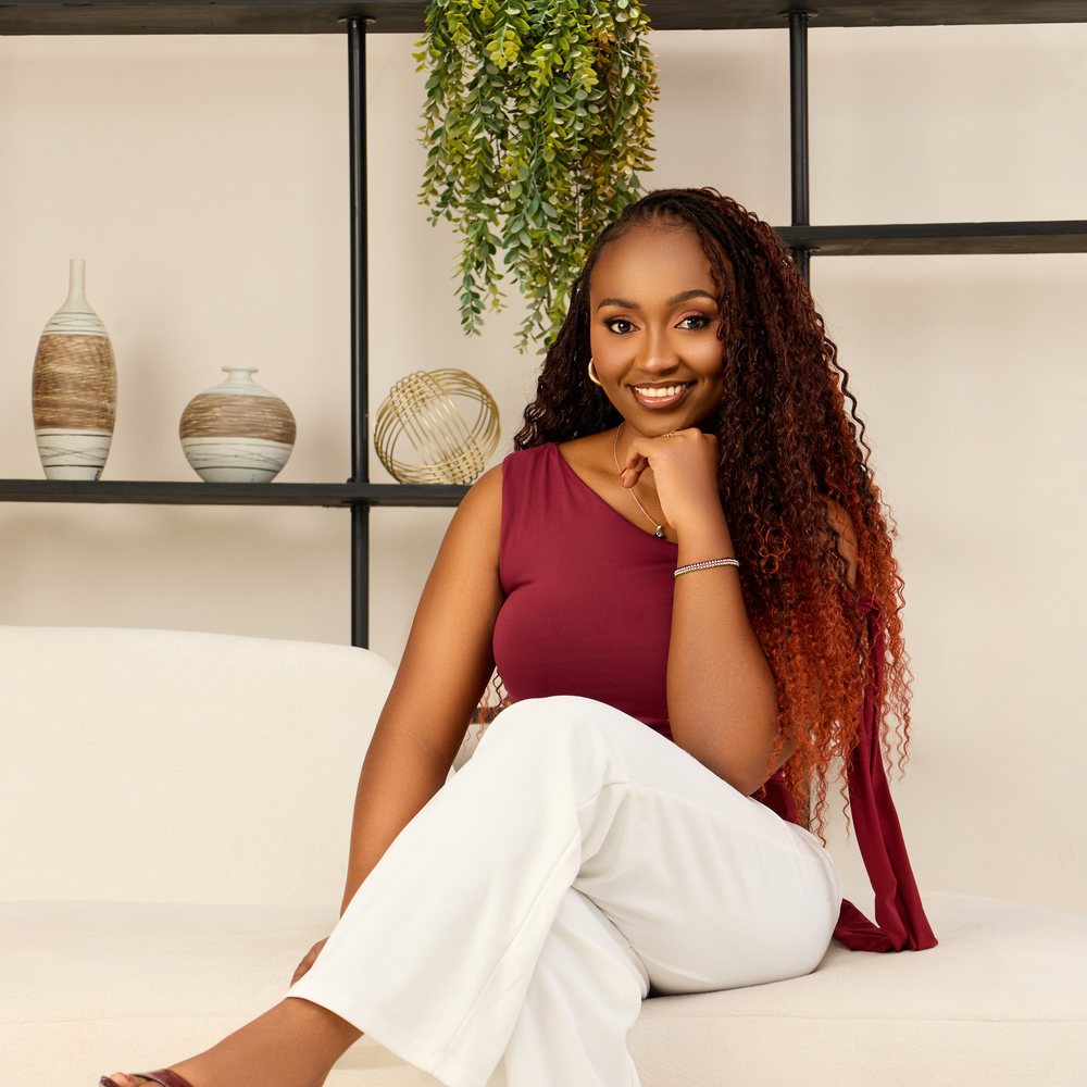 Tabitha Kavyu seated on a cream sofa in a wine-red top, smiling